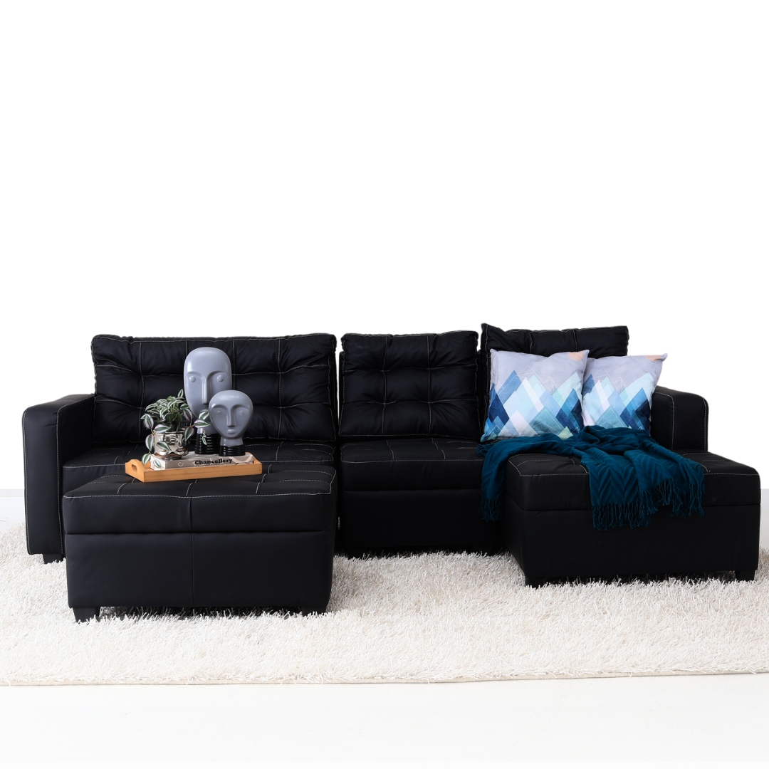 Black L-shape sofa with tufted upholstery, chaise section, and matching ottoman and pillows.