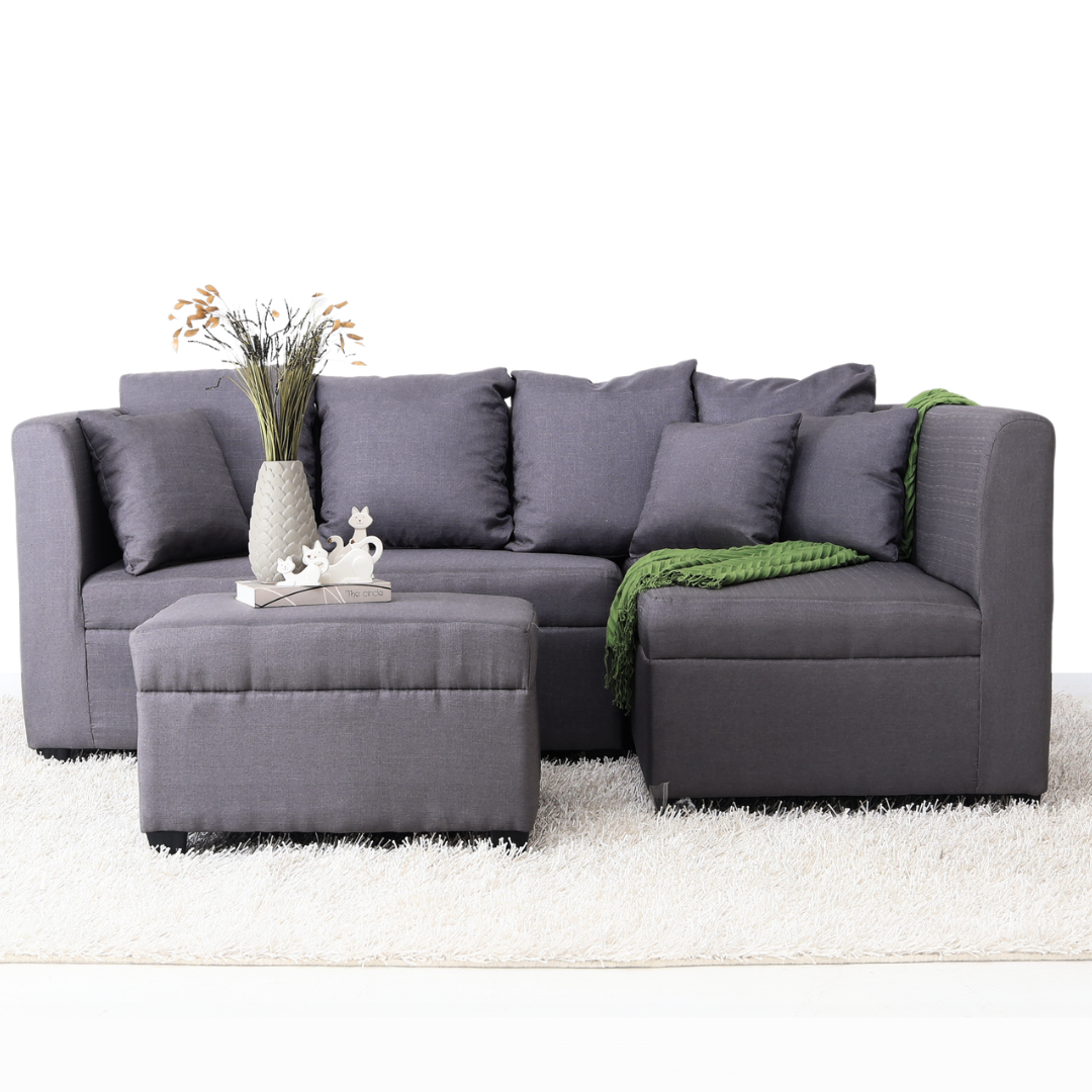 Gray L-shaped sofa set with chaise, decorative pillows, and a folded green throw.