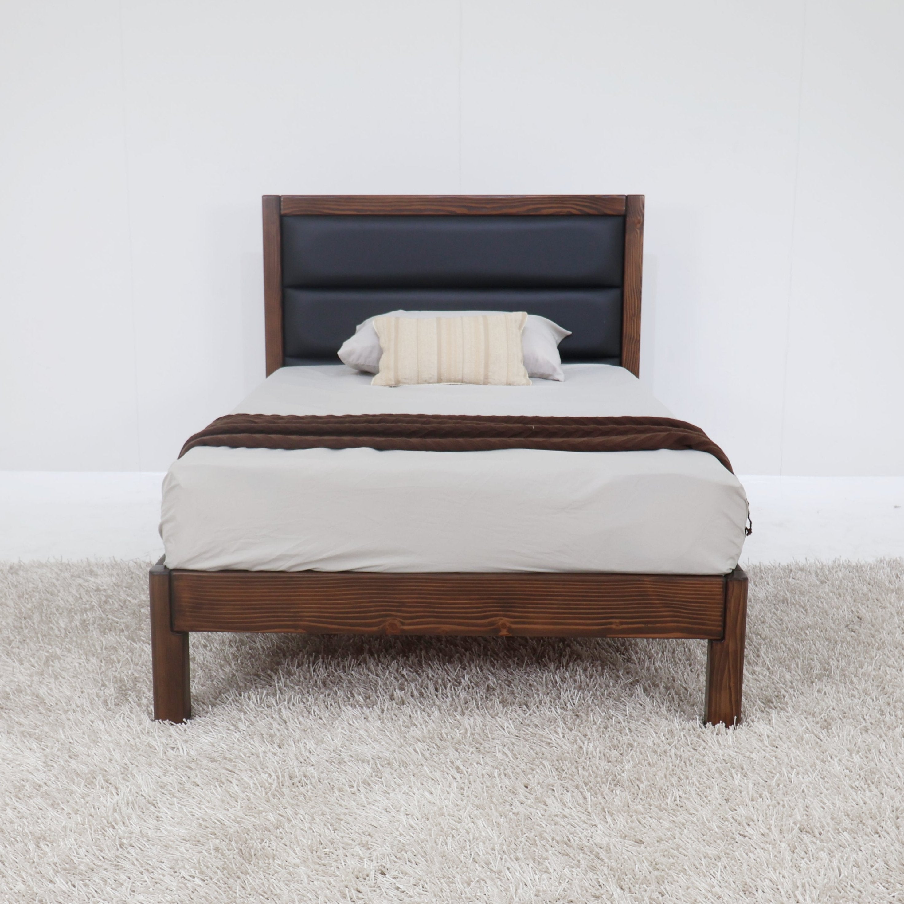 Dark headboard platform bed with brown wooden frame and white bedding