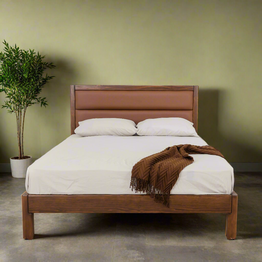 Brown double bed with padded headboard, white linens, and wood frame