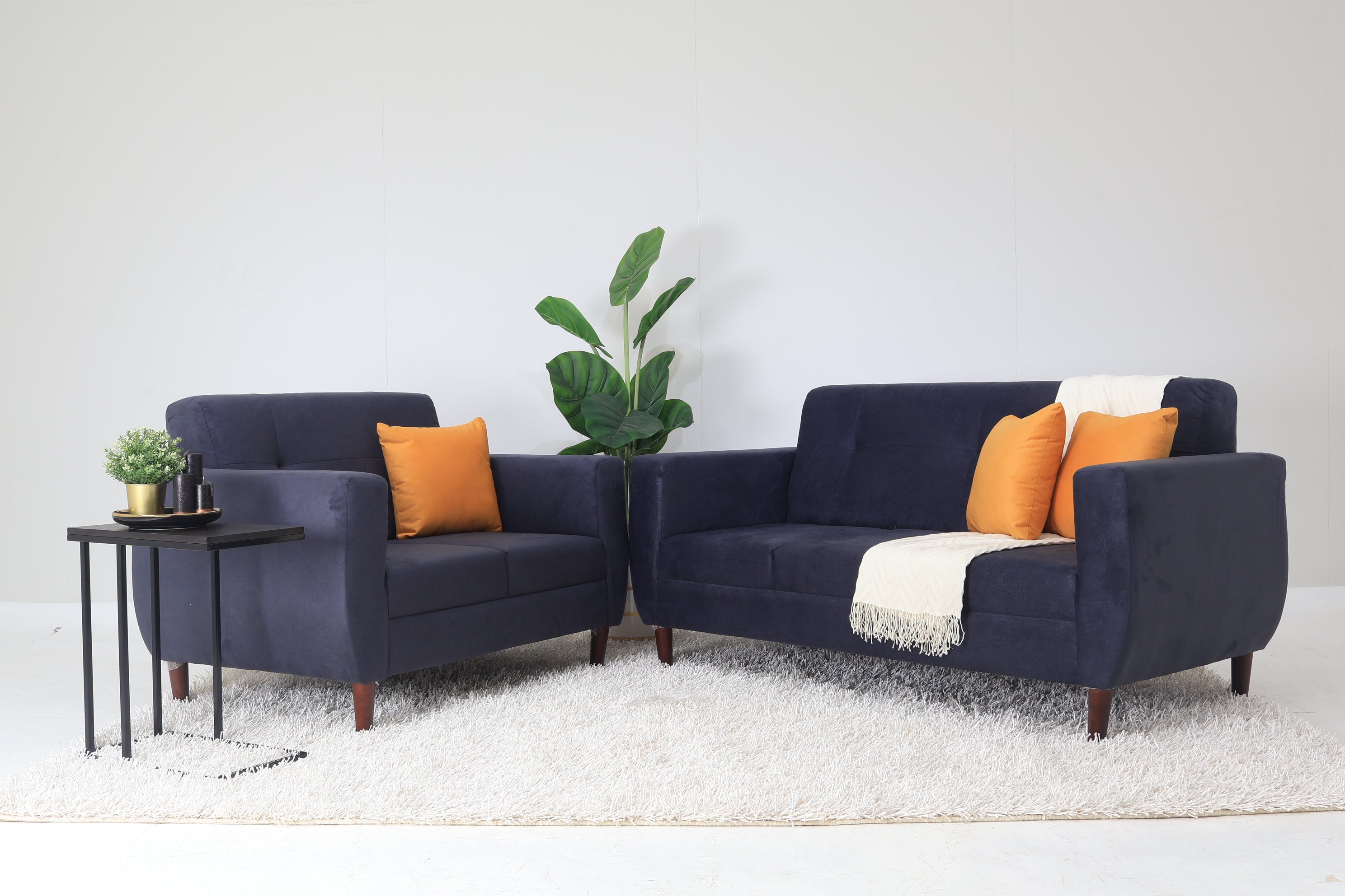Dark blue 2-seater sofa with orange pillows and white throw blanket