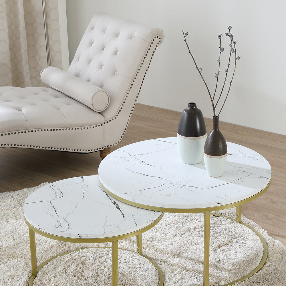 Round nesting coffee table set with white marble-look surface and gold frame near sofa