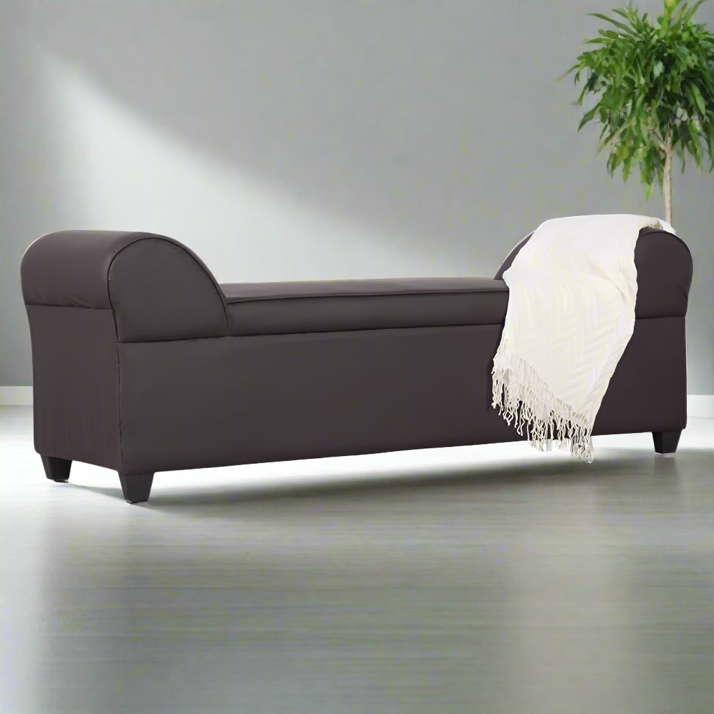 Lounge sofa in dark fabric with curved arms and off-white throw draped over seat