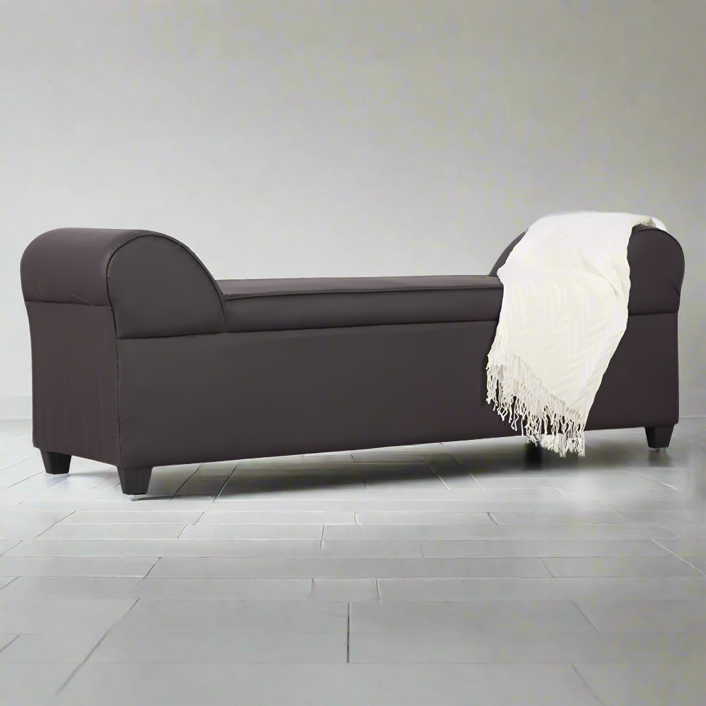 Lounge sofa in dark fabric with rounded arms, low back, and off-white throw on seat