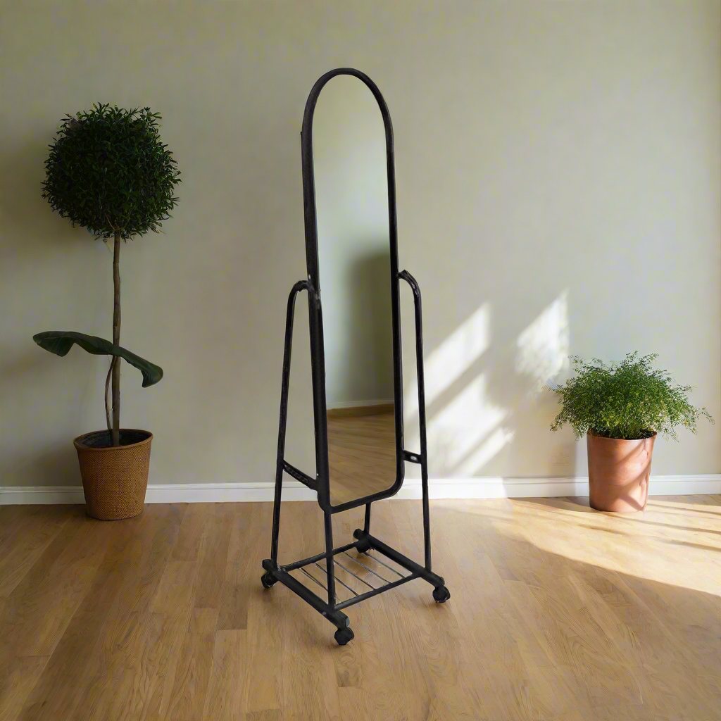 Black freestanding floor mirror with arched frame, metal lower shelf, and caster feet