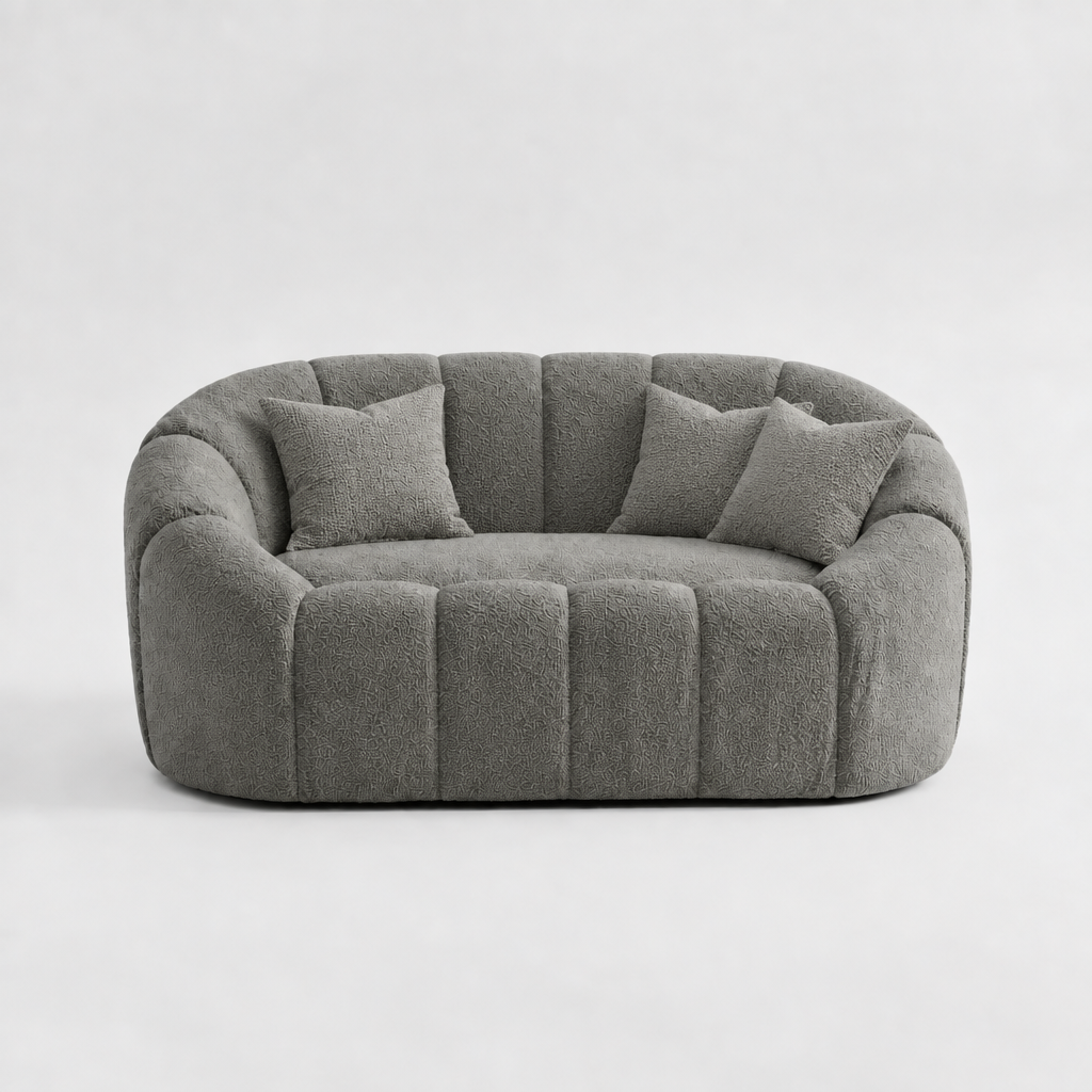 Gray 3-seater sofa, rounded arms and three back pillows over four vertical seat panels