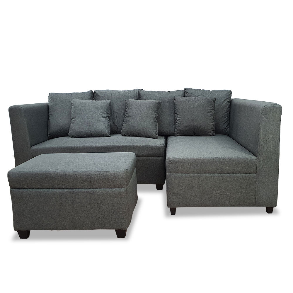 Gray L-shaped sectional with ottoman chaise and several square back pillows.